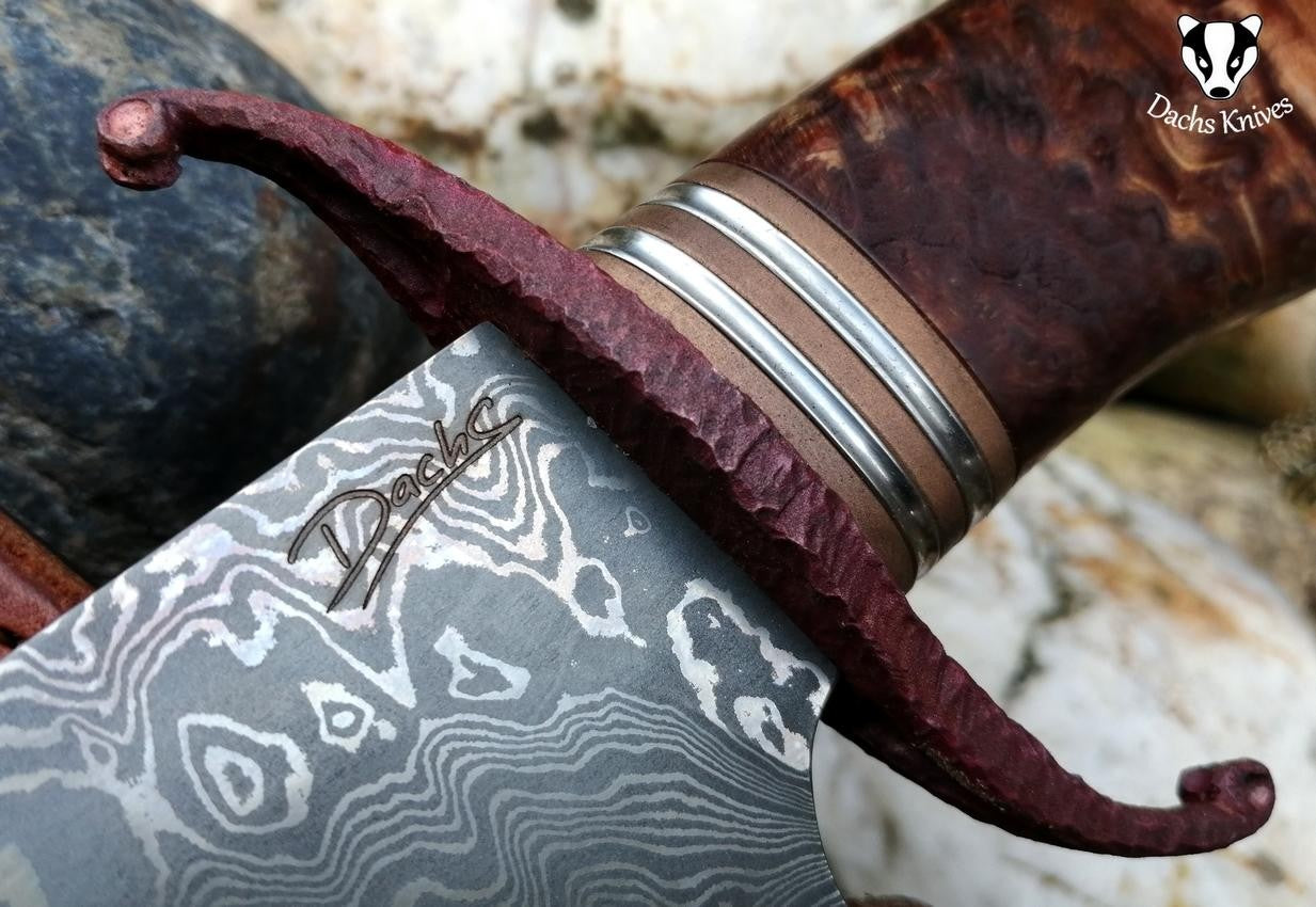 Detail rukojeti nože s ozdobnými prvky a koženým pouzdrem.