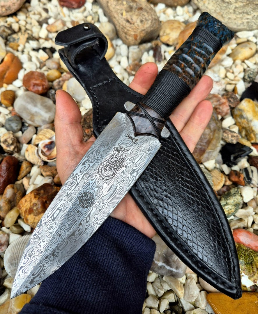 Nerezová dýka Damasteel s výraznou kresbou čepele a rukojetí z přírodního materiálu v ruce sběratele