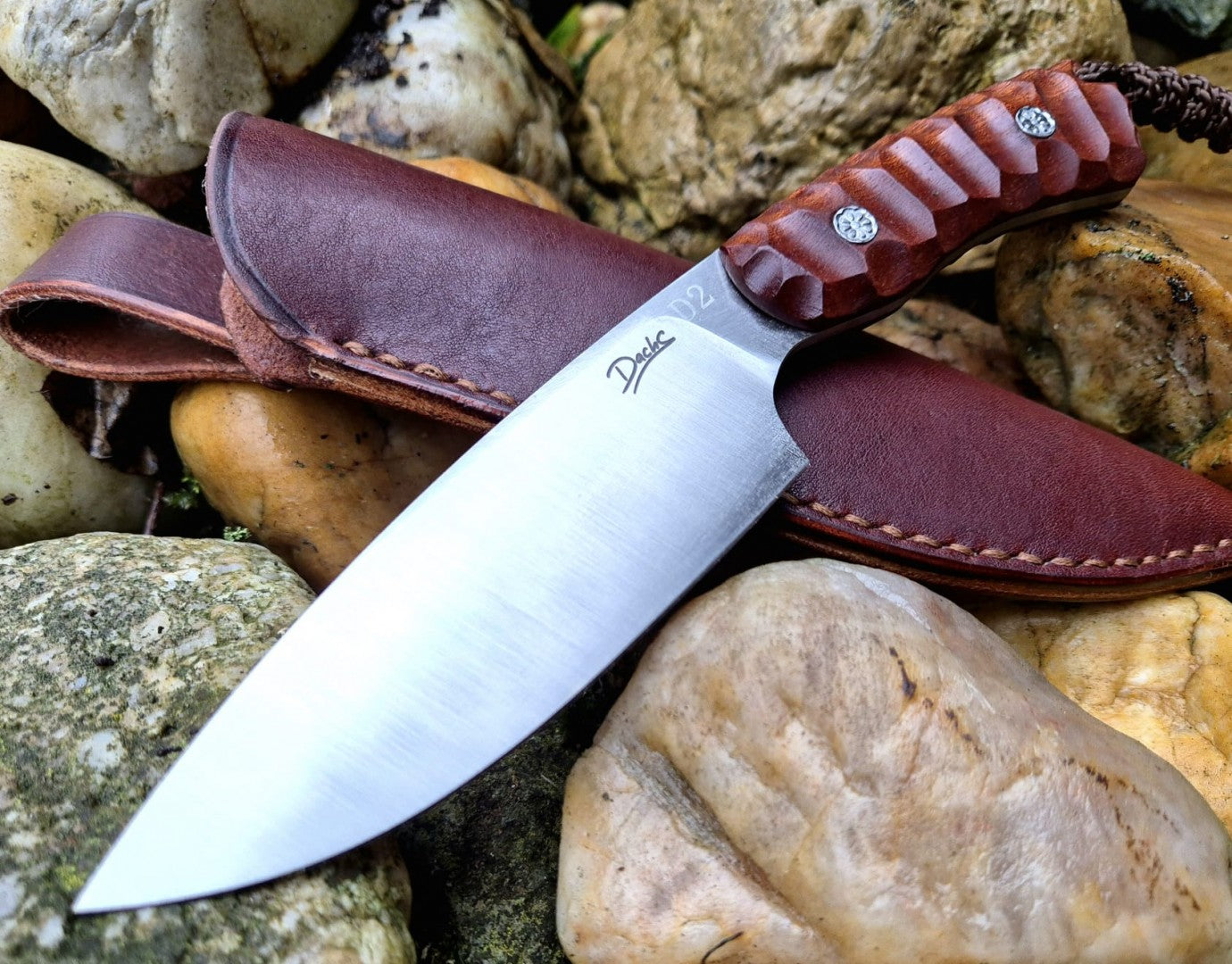 Ručně vyrobený outdoorový nůž s čepelí z nerezové oceli a ergonomickou rukojetí z exotického dřeva, doplněný koženým pouzdrem – ideální pro bushcraft, kempování a survival aktivity.