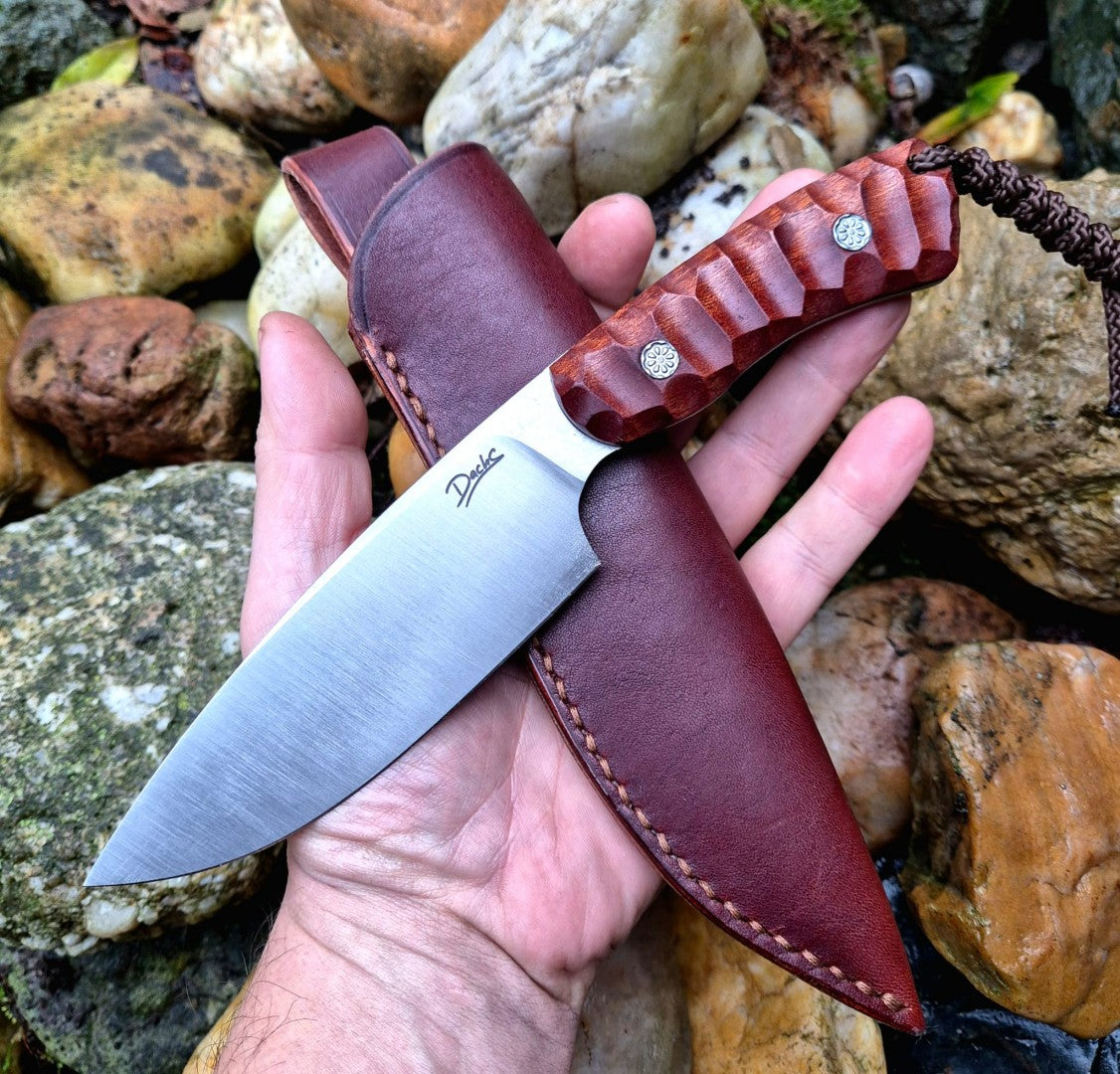 Ručně vyrobený outdoorový nůž s čepelí z nerezové oceli a ergonomickou rukojetí z exotického dřeva, doplněný koženým pouzdrem – ideální pro bushcraft, kempování a survival aktivity.