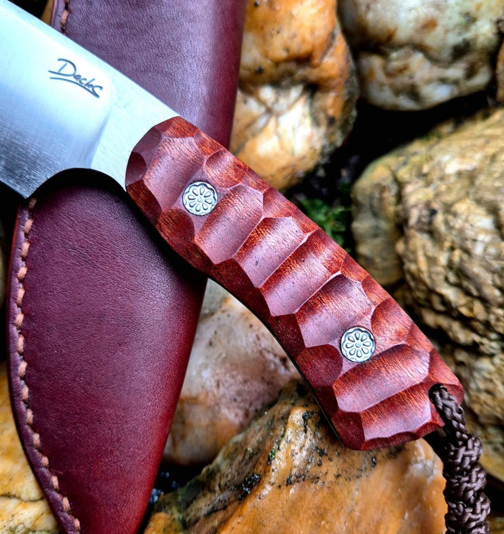 Ručně vyrobený outdoorový nůž s čepelí z nerezové oceli a ergonomickou rukojetí z exotického dřeva, doplněný koženým pouzdrem – ideální pro bushcraft, kempování a survival aktivity.
