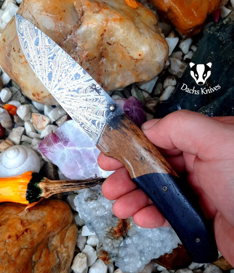 Zavírací nůž Gentleman s damaškovou čepelí položený na krystalech a minerálech